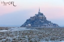 Mont Saint-Michel sous la neige au soleil levant.