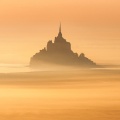 Le Mont Saint-Michel dans la brume orangée.
