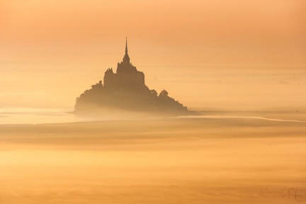 Le Mont Saint-Michel dans la brume orangée.